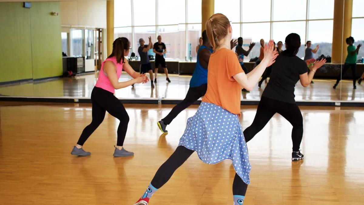 Personas siguiendo una clase de danza frente a un espejo.