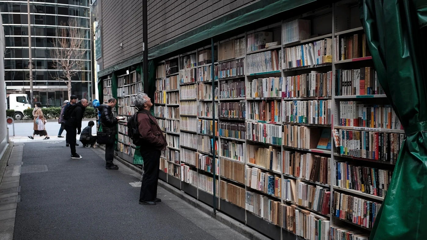 Persona de pie junto a estantes llenos de libros.