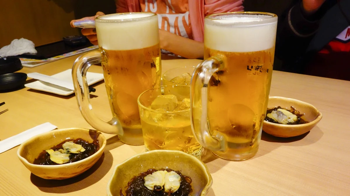 Jarras de cerveza y platos pequeños sobre una mesa de izakaya.