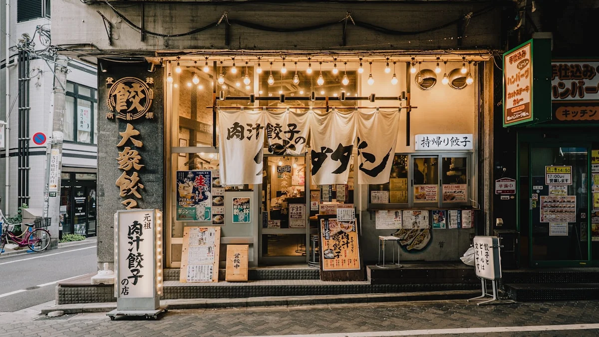 Fachada de un restaurante japonés con carteles y noren iluminados.